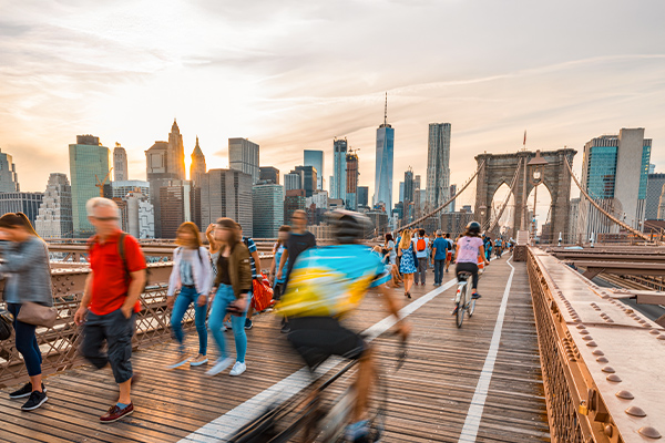 Fußgänger und Radfahrer auf der Brooklyn Bridge vor der Skyline von Manhattan.