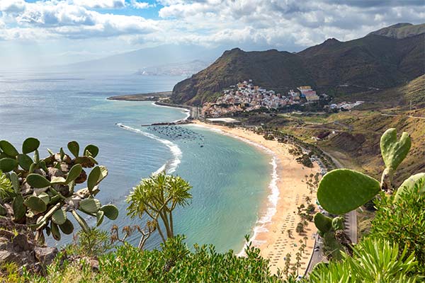 Panorama der Küste von Teneriffa mit Sandstrand, Bergen und dem Atlantischen Ozean.